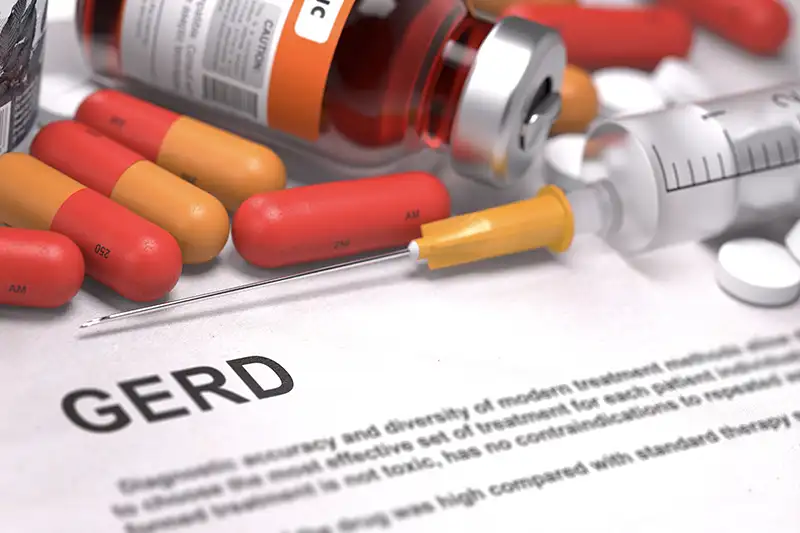 Medical concept image showing GERD text with pills, syringe, and medicine vial