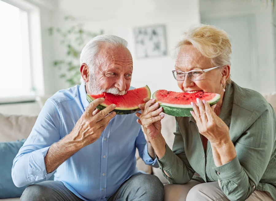 An elderly man and woman eating watermelon to reduce mucus in throat after acdf surgery