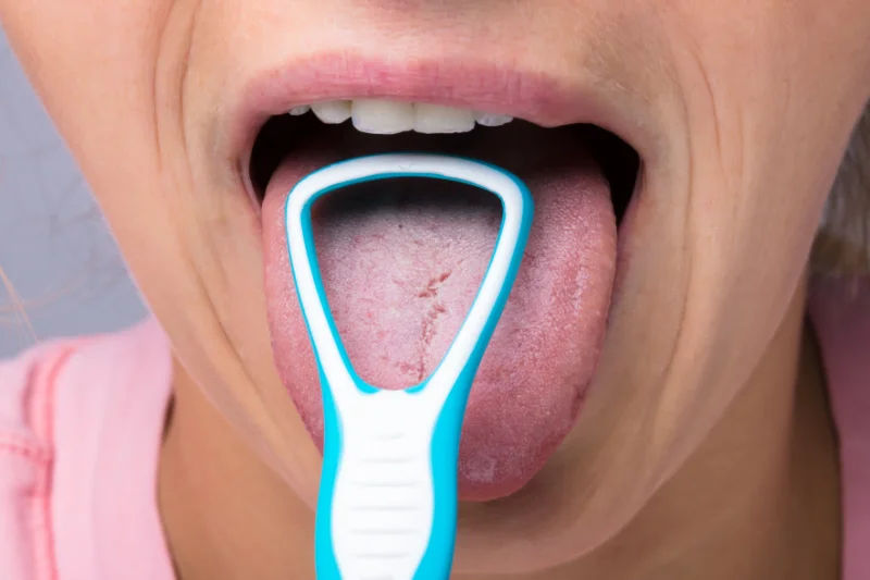 A person using a tongue scraper to try to get rid of metallic taste