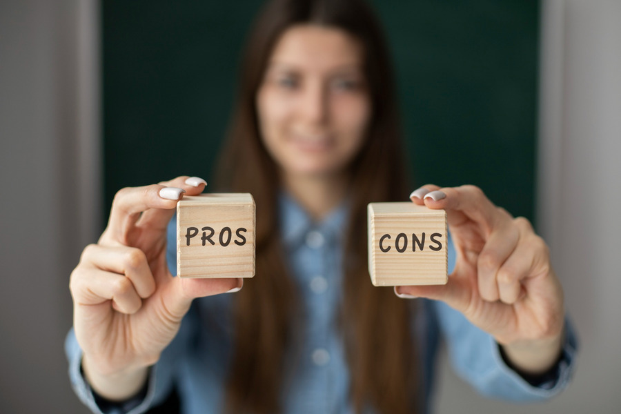 A lady holding blocks that say pros and cons to get the conversation started regarding the pros and cons of taking Xiidra over some other dry eye therapies.