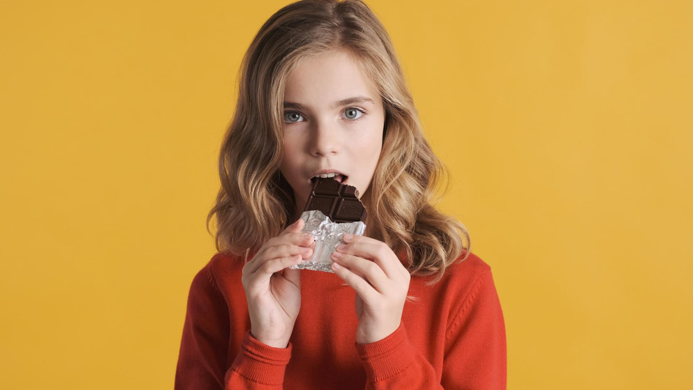 A lady enjoying the bitterness of a chocolate bar as the compounds in the chocolate meet the taste receptors on her taste buds.