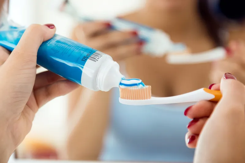  A person about to brush their teeth to improve their oral health in an attempt to get rid of the metal flavor in mouth they’ve been experiencing. 
