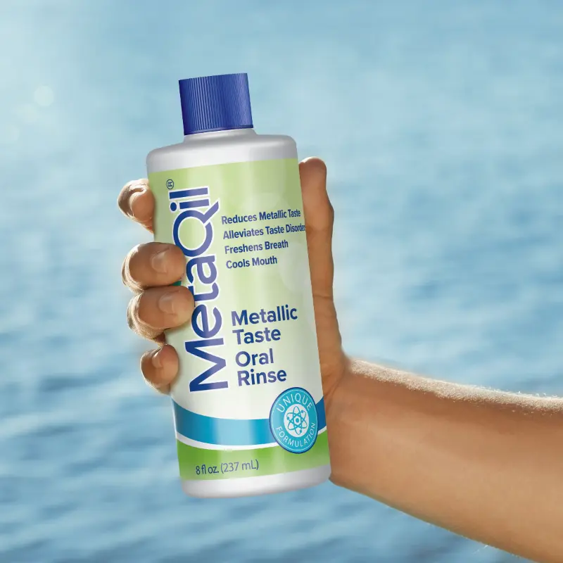 A hand holding a bottle of MetaQil, as the best solution for how to get rid of metallic taste.